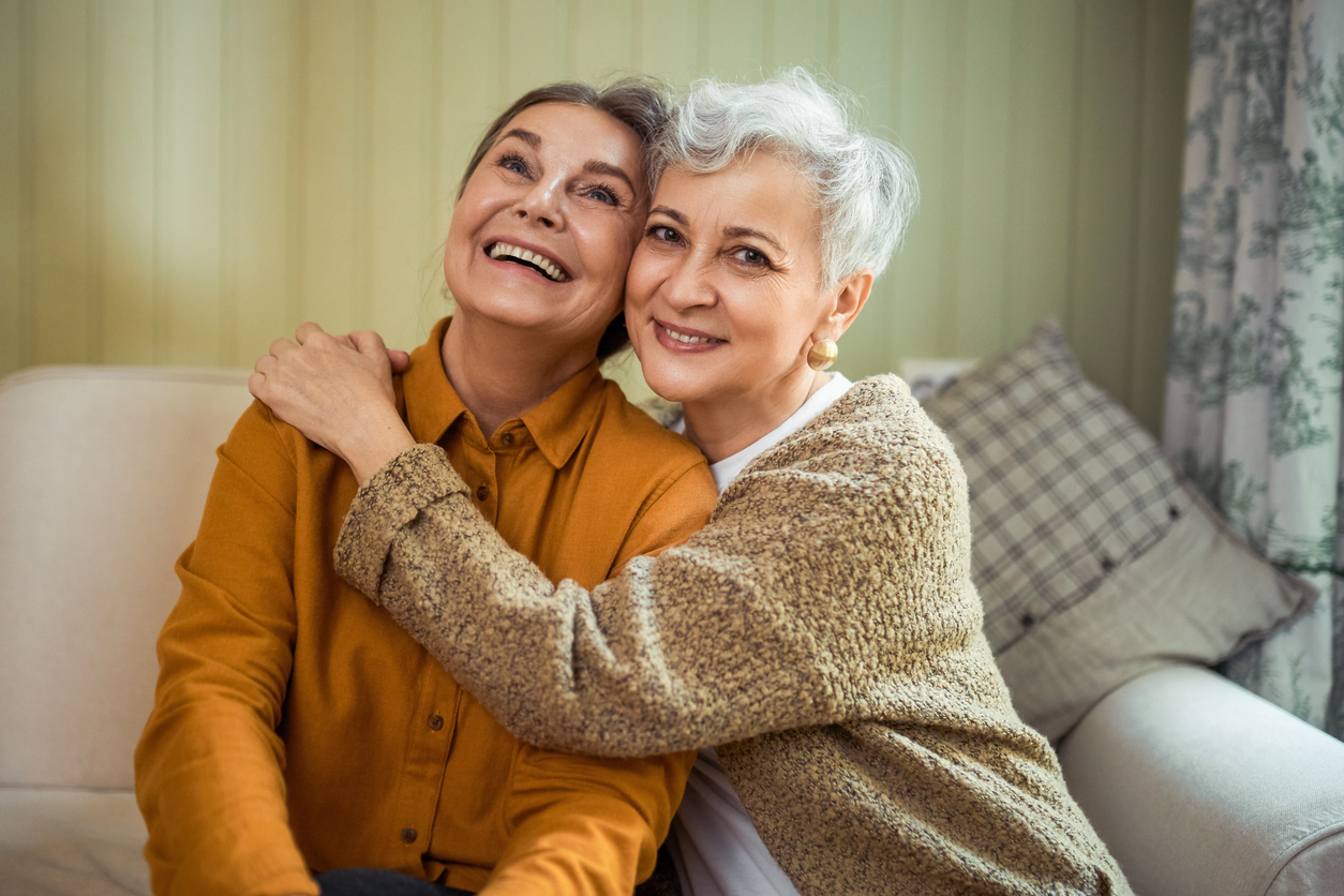 two senior women smiling and hugging